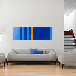 Acrylglasbild ‘Blue is all I ever wanted’ im Format 180x60 cm, als modernes Wandbild in einem stilvollen Wohnzimmer mit grauen Sofas und Treppenaufgang im Hintergrund.