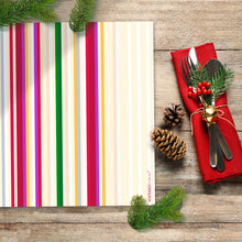 Papier-Tischset Colourful Celebration mit festlichem Streifendesign, arrangiert auf Holztisch mit Tannenzweigen und Besteck.